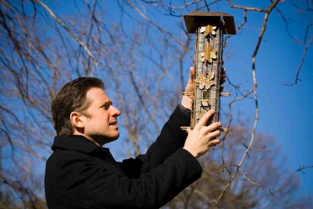 man hanging a bird house