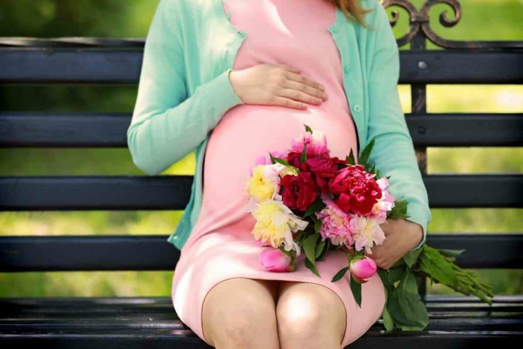 Pregnant woman holding Peony flowers blooming