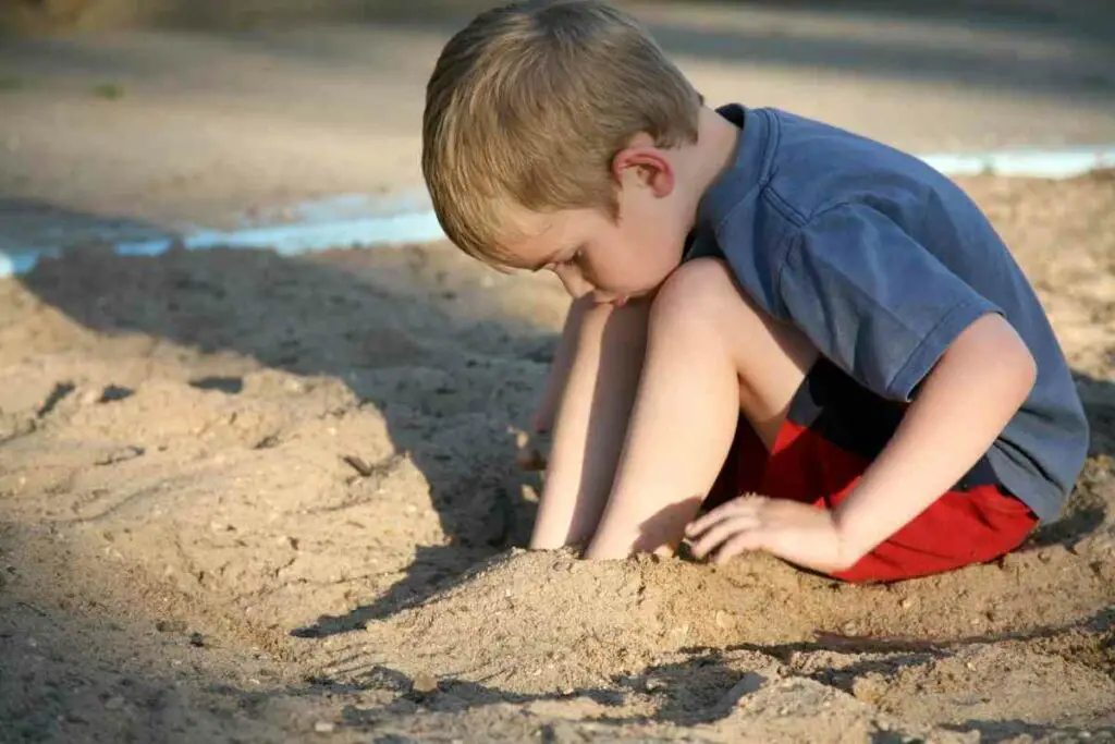 A small boy is having fun in a sandbox