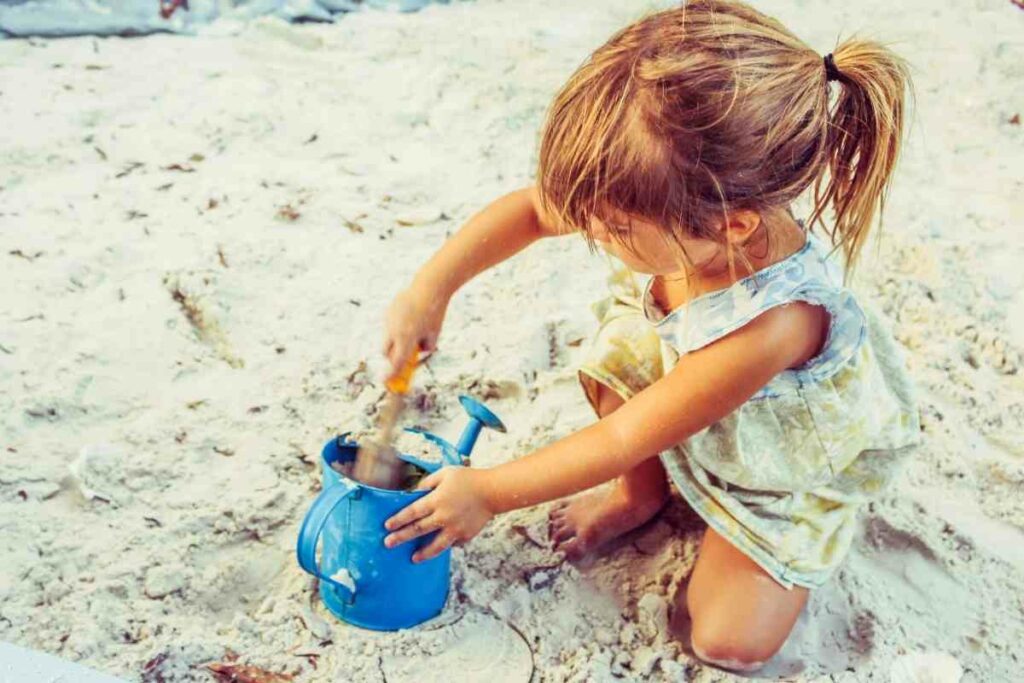 A small girl is having fun in a sandbox