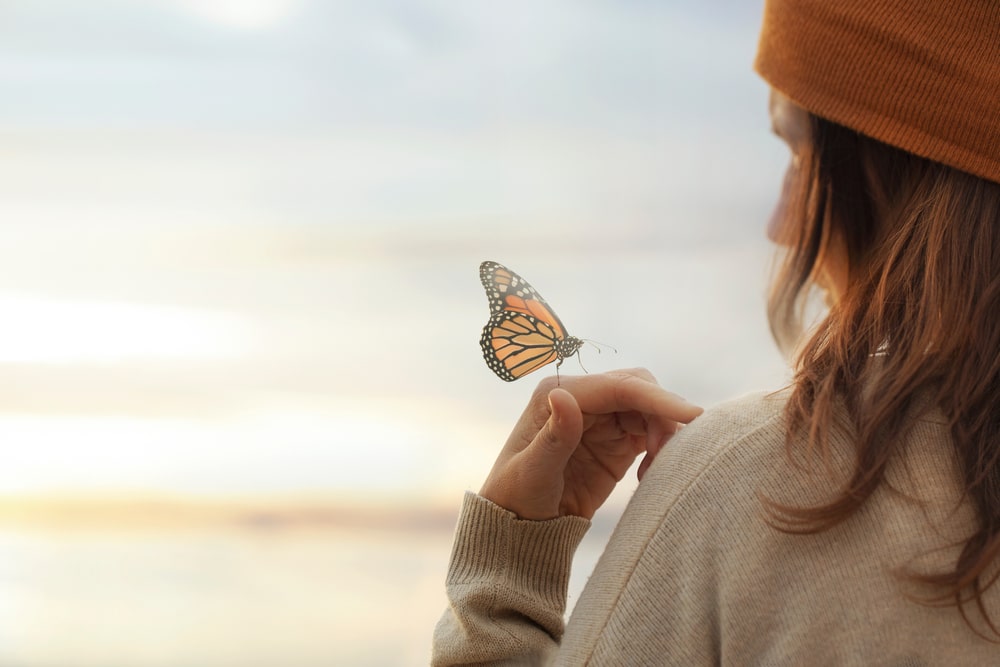 A butterfly on a woman's hand.