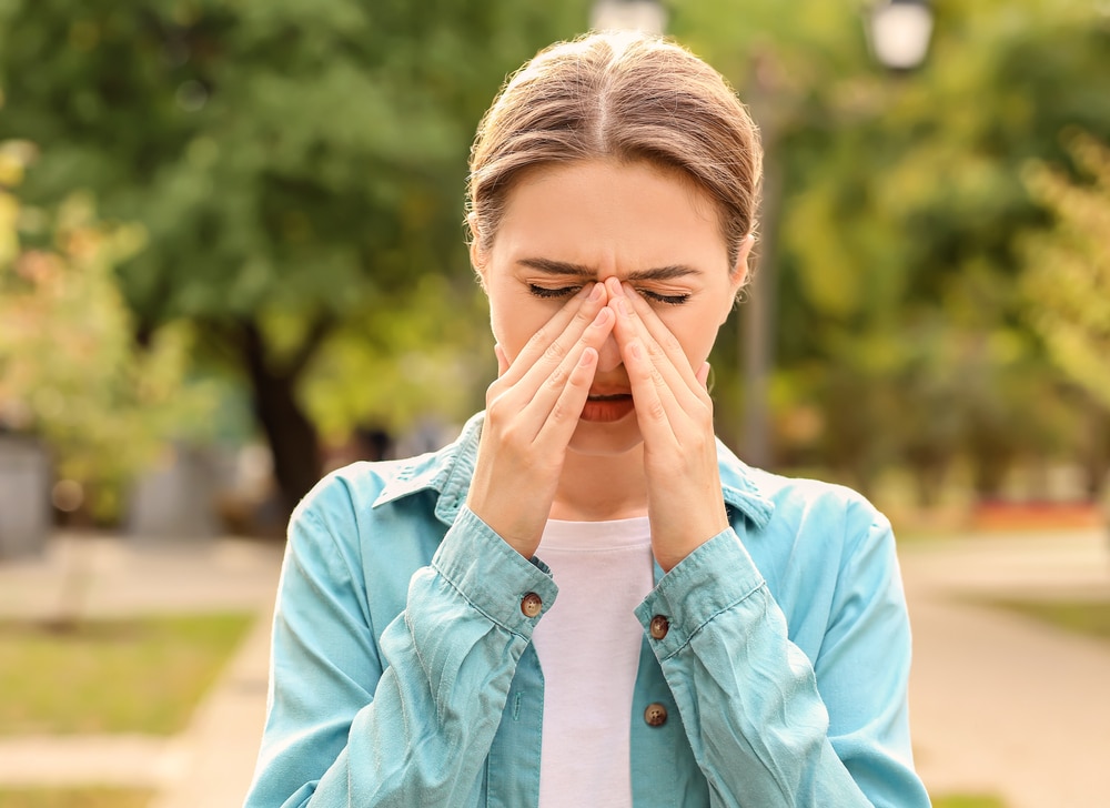 A woman rubbing her nose and dealing with allergies.