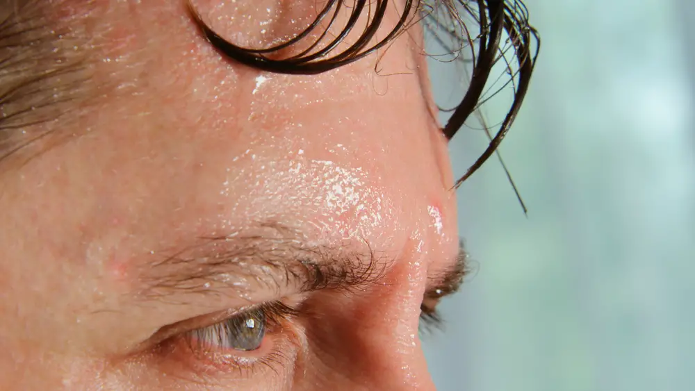 A closeup of a sweaty man's forehead and upper face.