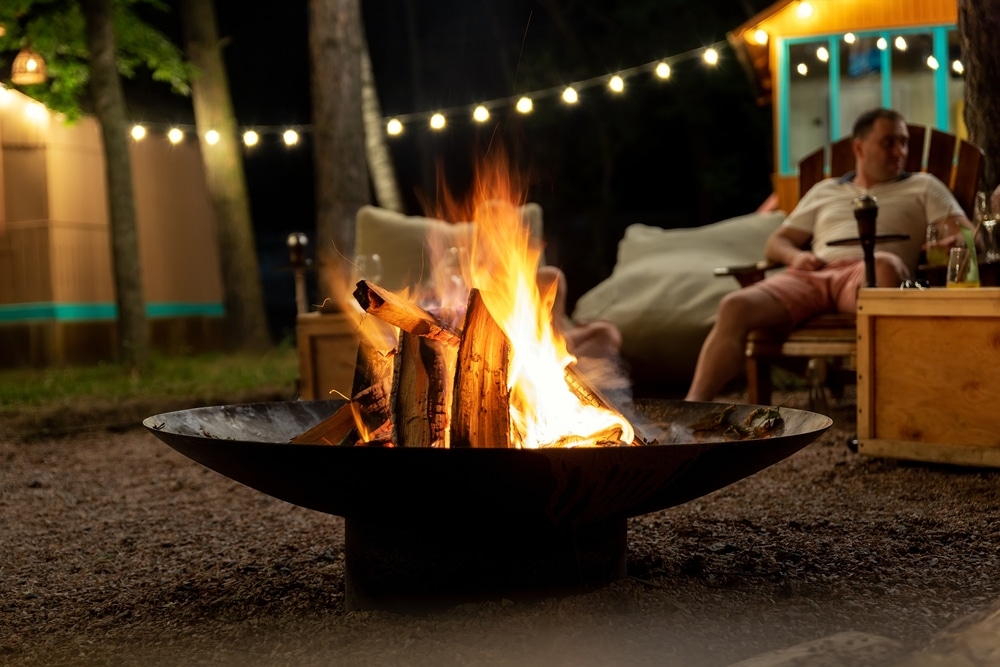 A man relaxing in his backyard with a fire.