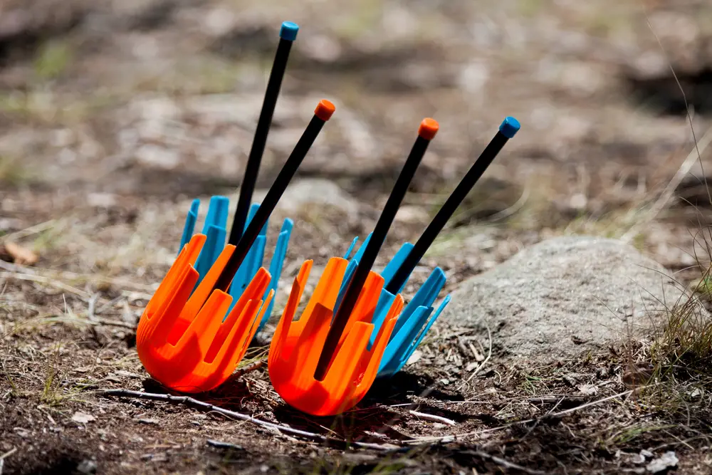 Four safe lawn darts on the ground, two of which are orange and two of which are blue.