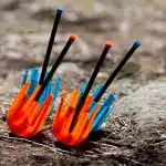 A pair of safe orange lawn darts next to a pair of safe blue lawn darts.