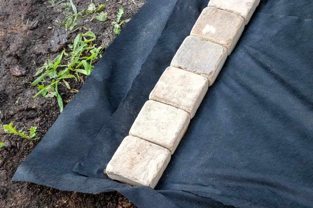Edging stones laid over top of landscape fabric.