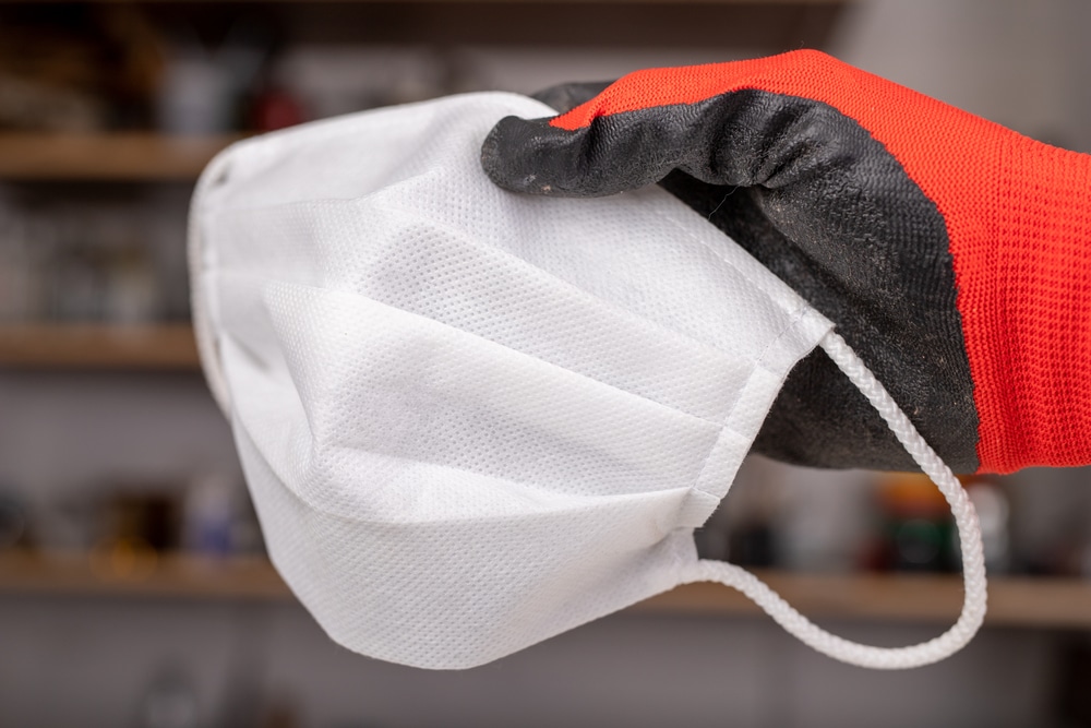 A closeup of a gloved hand holding a dust mask.