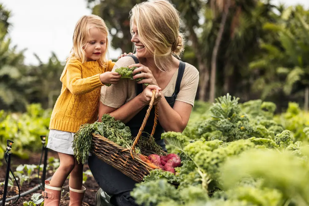 A happy mother picking vegetables with her daughter.