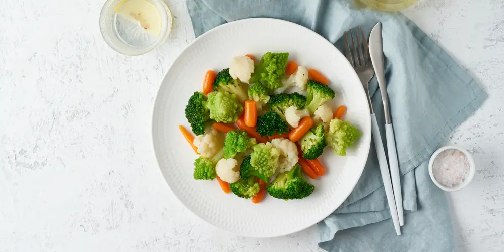 A plate of vegetables, such as cauliflower, broccoli, and carrots.