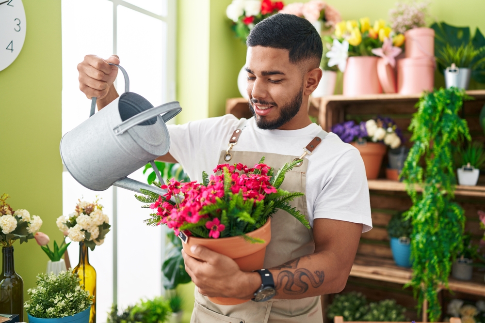 A man watering a plant in a florist shop.