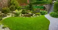 Large garden with a stone path and walls and grass.