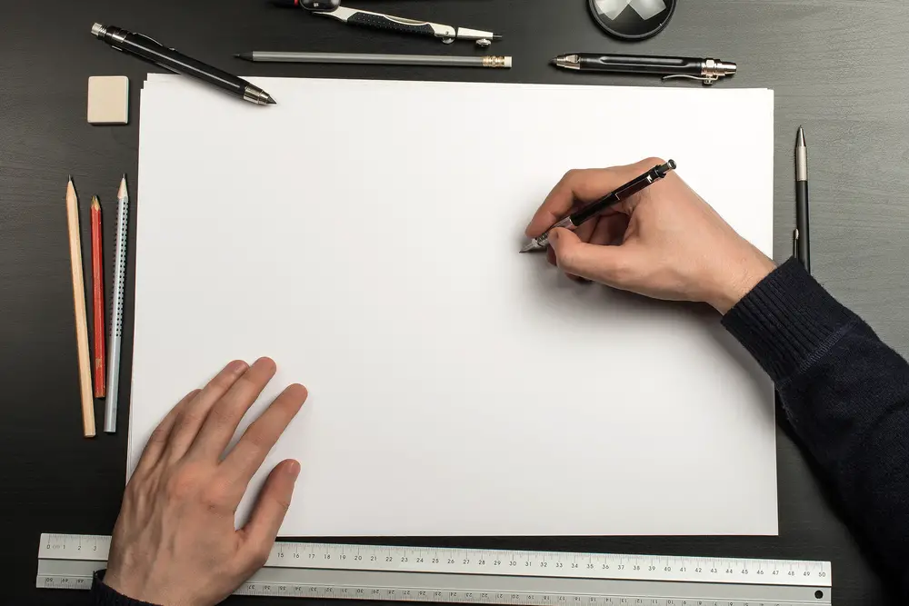 Overhead view of a person about to draw on sketch paper.