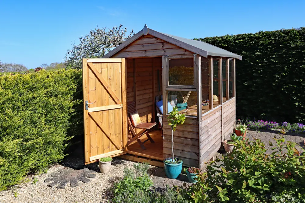 A potting shed in a backyard garden on a sunny day.
